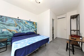 Un dormitorio con cama, escritorio y un cuadro abstracto grande en la pared.