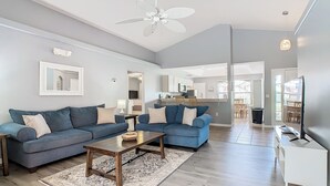 Ein modernes Wohnzimmer mit zwei Sofas, einem Couchtisch und einem Deckenventilator.