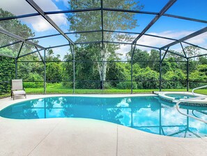 Ein überdachter Pool mit Glasdach, umgeben von üppiger Vegetation.