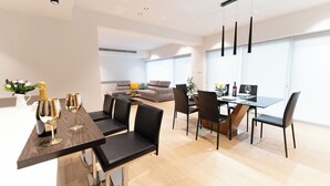 Un moderno comedor con una mesa y sillas negras, un sofá y un amplio ventanal al fondo.