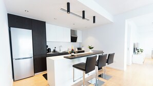 Una cocina moderna con una isla central, taburetes de bar y un refrigerador empotrado.