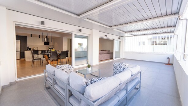 Un espacio moderno para estar con un conjunto de sofás, una mesa de comedor y una cocina al fondo.