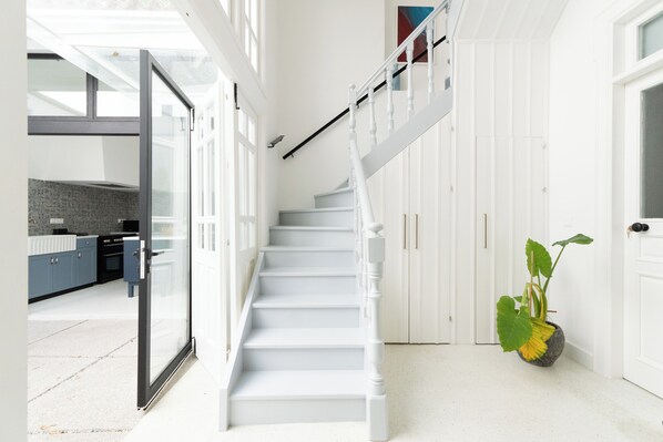 A modern staircase with white railings and a glass door leading to a kitchen area.