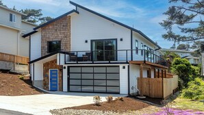 Ein modernes, zweistöckiges Haus mit Garage, Balkon und einer Holzterrasse.