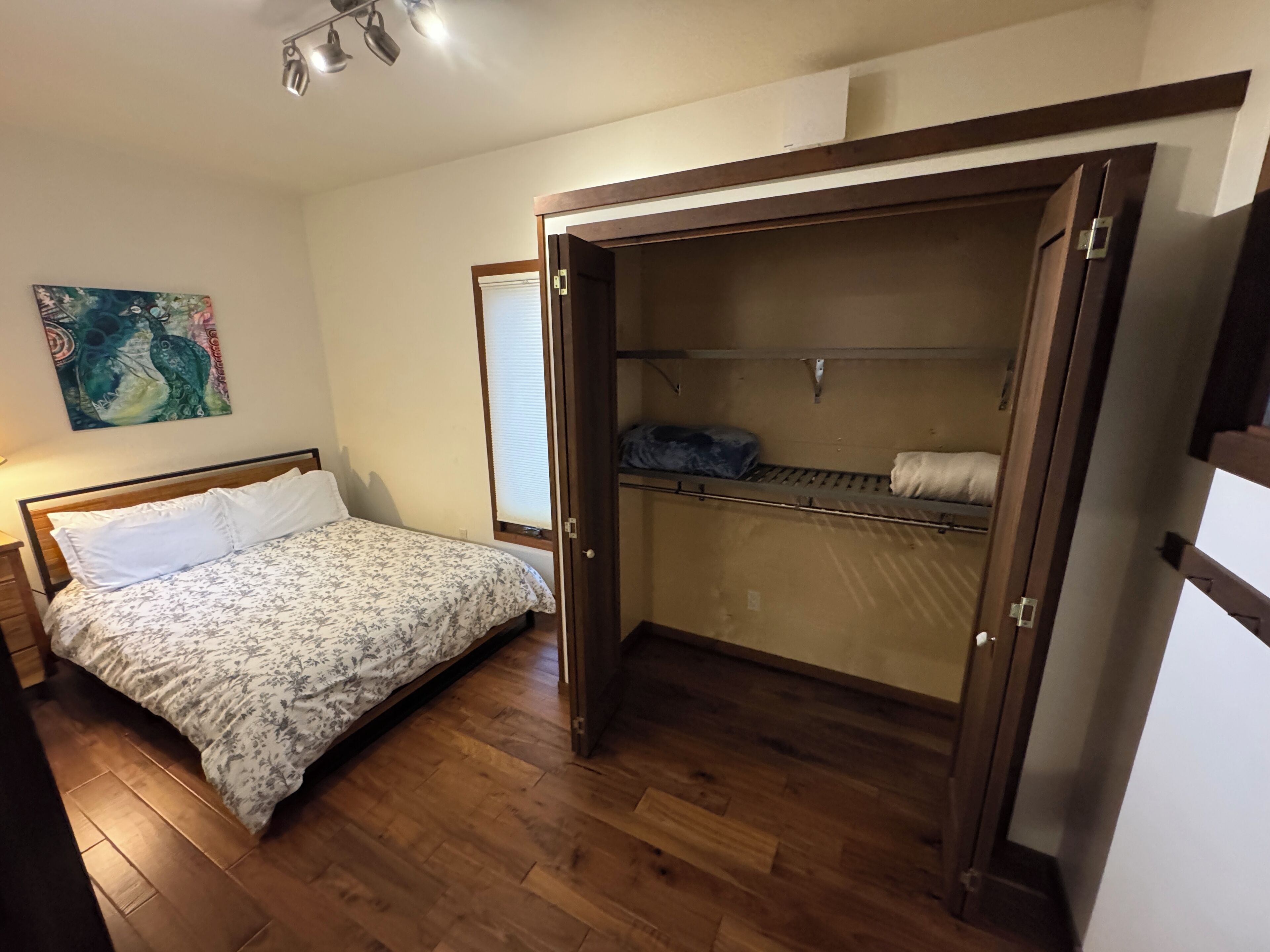 Une chambre à coucher avec un lit, une armoire et un tableau accroché au mur.