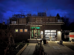 En moderne bygning med to etager, en garage, et overdækket udendørsområde og en sti til indgangen.