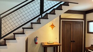 A staircase with a glass railing, a wooden table with a decorative item, a fire extinguisher, and a piano. - Perfect location! Downtown Beach & Ski Pad w/hot tub in the heart of Sandpoint. (Sandpoint)