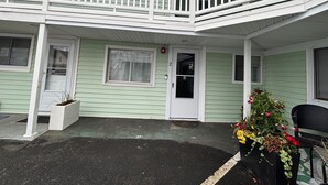 A two-story building with a balcony, a front door, and a small porch area with a chair and potted plants. - Idyllic 3 Bed/2Bath condo in Old Orchard Beach, steps to the beach (Old Orchard Beach)