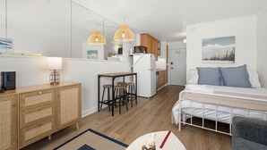Een compact appartement, modern ingericht, met een kitchenette, een eethoek en een slaapkamer.