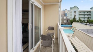 Een balkon met een schuifdeur, een zwembad en uitzicht op andere gebouwen.