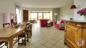 Ein geräumiges Wohnzimmer mit einem Holzespeise Tisch, roten Sofas und einem Holzkabinett.