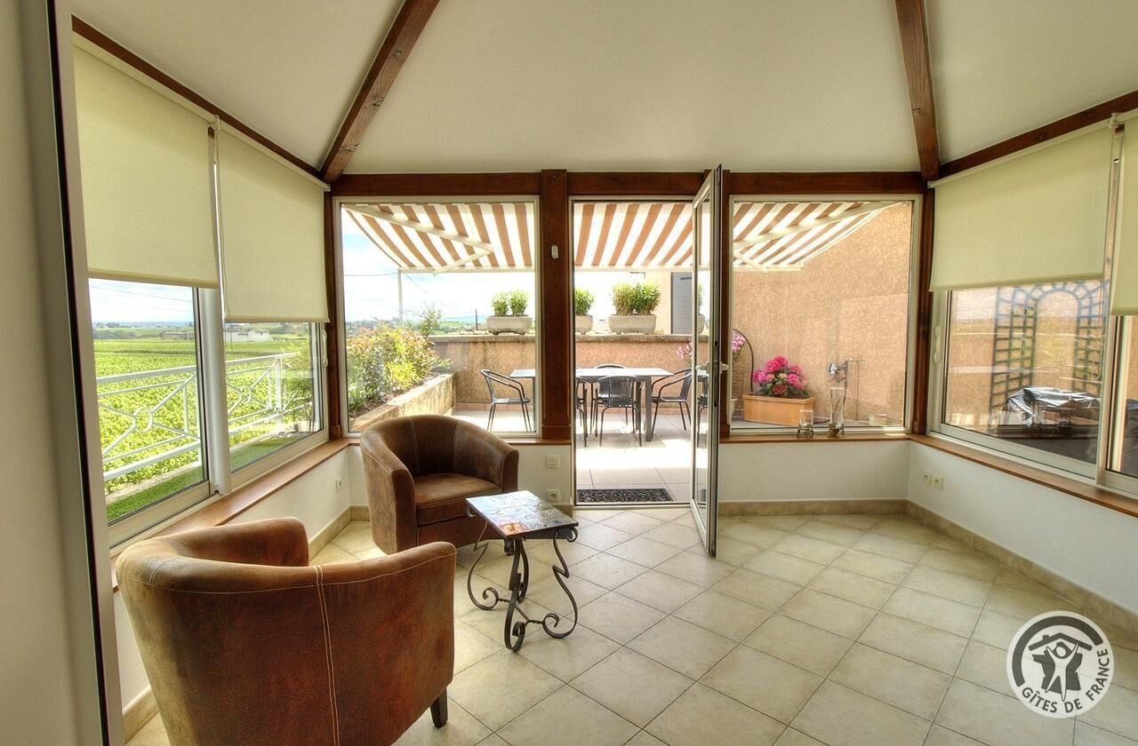 Ein Zimmer mit Blick auf einen Garten, ein Balkon mit Tisch und Stühlen sowie eine Tür zum Außenbereich.