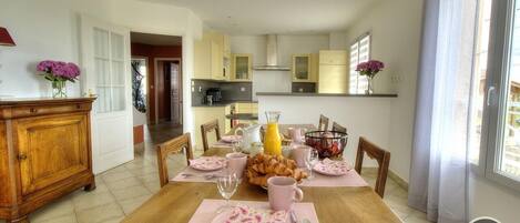 Comedor con mesa de madera dispuesta para el desayuno, con cruasanes y café.