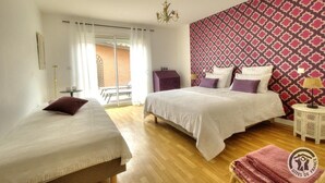 Ein Schlafzimmer mit zwei Betten, einer Wand mit Muster, einer Chandelier und einem Balkon mit Aussicht.