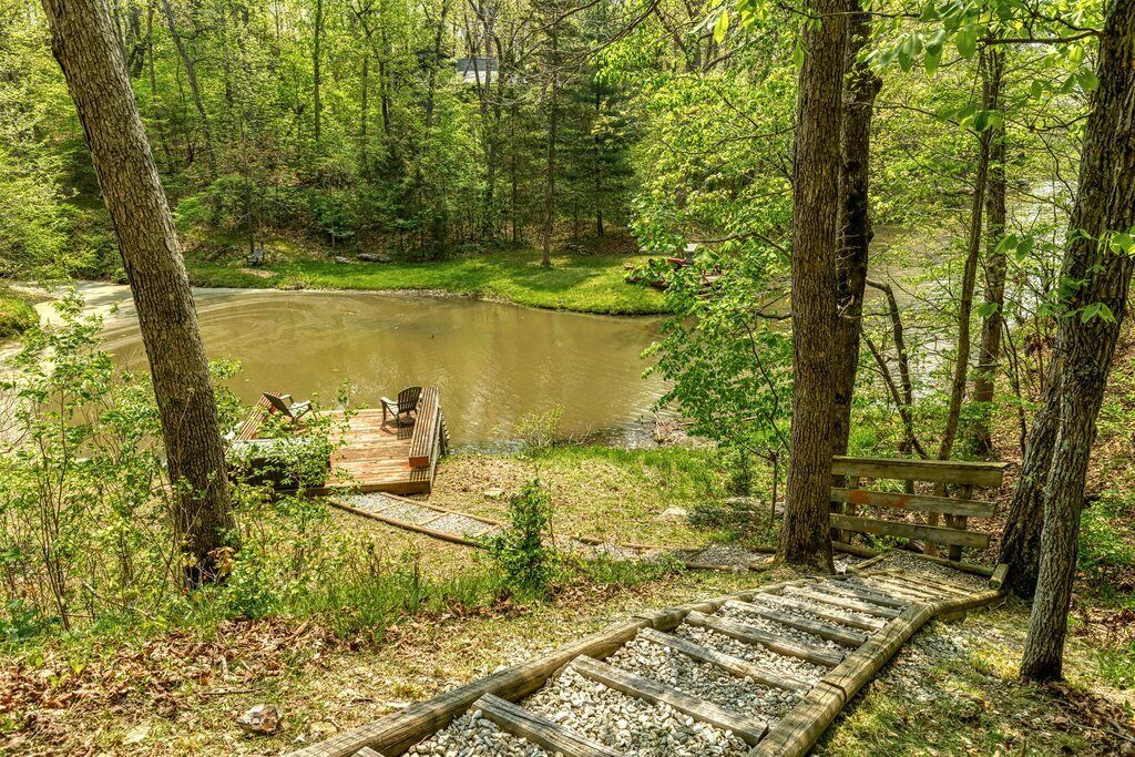 A wooden deck leading to a pond surrounded by trees.
