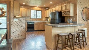 Une cuisine de style rustique, avec des éléments en bois, un îlot central, des tabourets de bar et des appareils électroménagers intégrés.