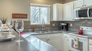 A modern kitchen with white cabinets, a large window, and a stainless steel microwave. - Innsbrook Home | Lake + Resort Access (Innsbrook)