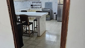 A kitchen with a tiled floor, a central island, and white cabinets.