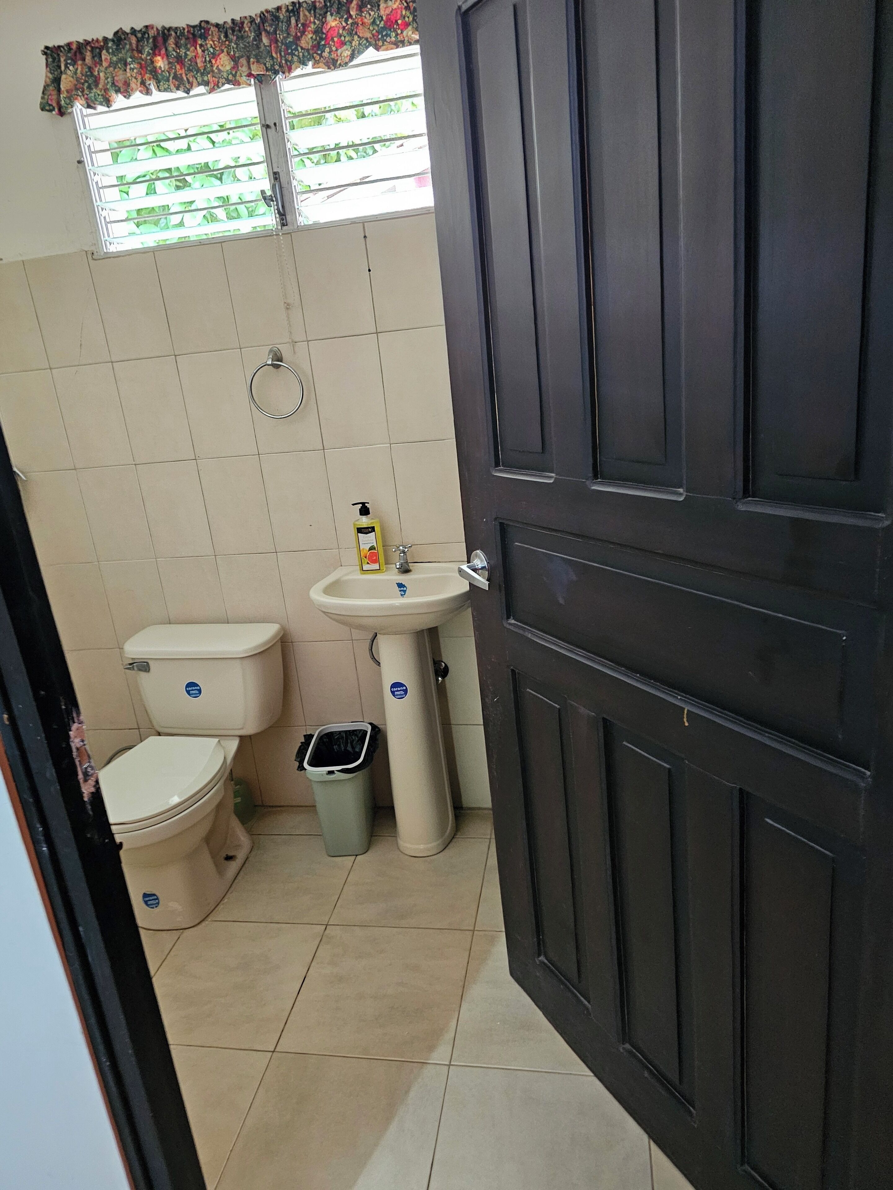A small bathroom with a toilet, sink, and trash bin.