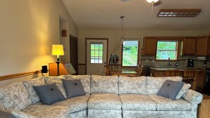 A living room with a sectional sofa, a wooden coffee table, and a dining area with a table and chairs. - Beautiful Misty Mountain Views from a quaint cottage in Maggie Valley! (Maggie Valley)