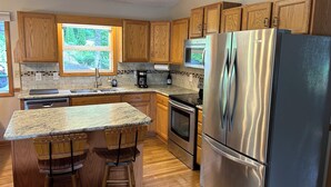 A kitchen with wooden cabinets, granite countertops, stainless steel appliances, and a window providing natural light. - Beautiful Misty Mountain Views from a quaint cottage in Maggie Valley! (Maggie Valley)