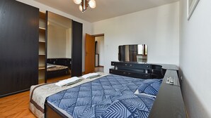 Ein Schlafzimmer mit Bett, Kommode, Spiegel und einer Deckenleuchte.