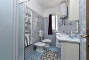 A bathroom with a toilet, bidet, and sink, tiled in blue and white, with a patterned rug on the floor. - Apartment 2361/116562 (Istria - Muntic), 10000m from the beach (Muntic)