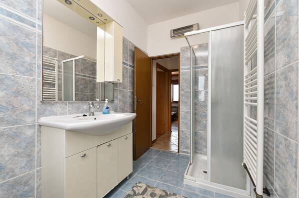 A bathroom with a sink, mirror, and shower.
