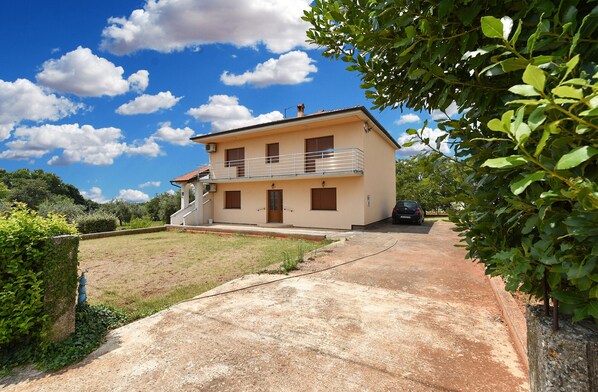 A two-story house with a balcony, a driveway, and a car parked in the driveway. - Apartment 2361/116562 (Istria - Muntic), 10000m from the beach (Muntic)
