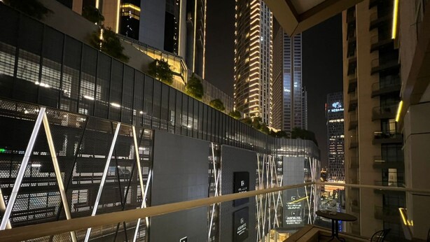 A modern hotel interior with a balcony overlooking a cityscape at night. - 3-bedroom hostel in lovely Dubai with Wi-Fi, AC, fitness room, breakfast (Dubai)