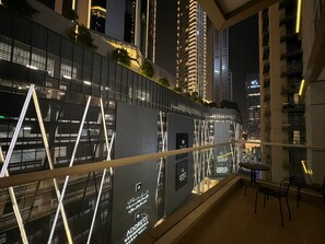 Ein modernes Hotelzimmer mit Balkon und Blick auf die beleuchtete Stadt bei Nacht.