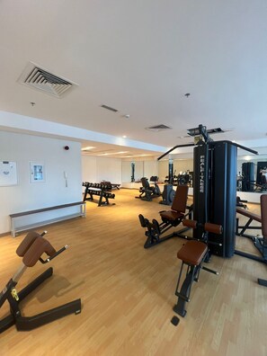 Ein Fitnessstudio mit verschiedenen Trainingsgeräten, darunter Kraftgeräte und Kurzhanteln.