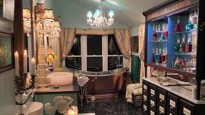 A luxurious room with a large bathtub, a chandelier, and a display of perfume bottles. - Designer Decorated Estate in Historic Downtown Lewisburg, West Virginia (Lewisburg)
