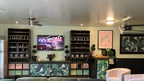 A living room with a green sofa, wooden shelves, a television, and a ceiling fan. - Designer Decorated Estate in Historic Downtown Lewisburg, West Virginia (Lewisburg)