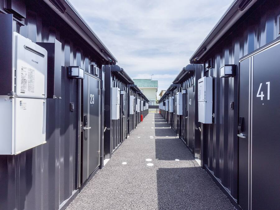 A corridor lined with numbered lockers, leading to a building with a green roof.