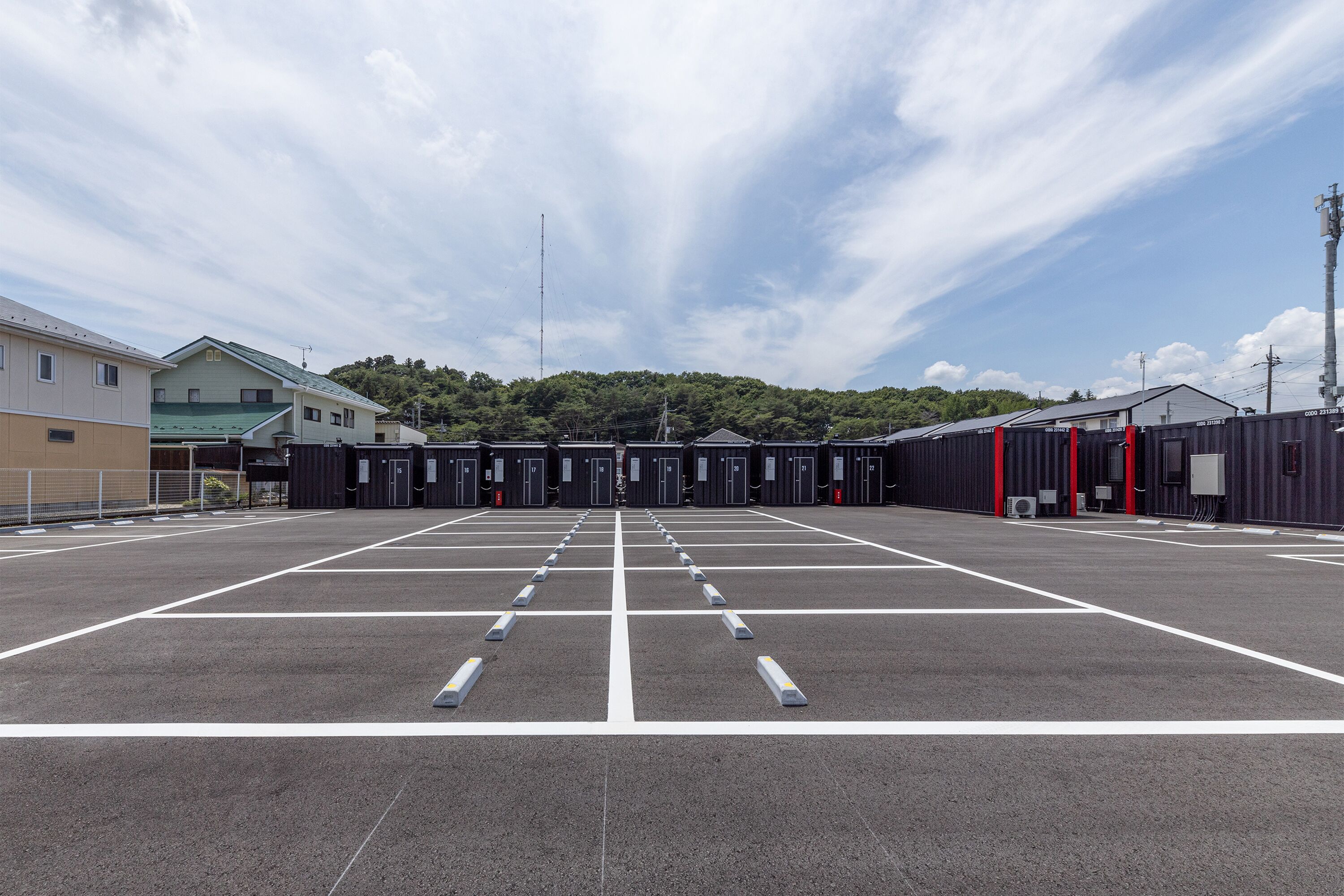 Um estacionamento com vagas demarcadas e uma fileira de edifícios ao fundo.