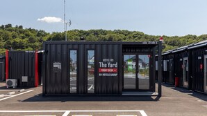 A compact hotel structure with a clear sign reading "HOTEL R9 The Yard FRONT DESK R9 HOTELS GROUP."