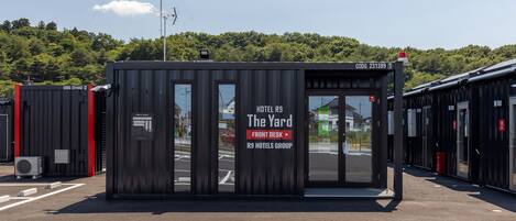 Una estructura hotelera compacta con un letrero claro que dice "HOTEL R9 The Yard FRONT DESK R9 HOTELS GROUP".