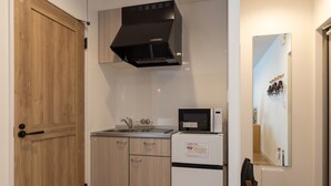 A compact kitchen with a wooden door, a microwave, and a small refrigerator.