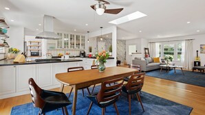 Una cocina moderna con armarios blancos, una mesa de comedor de madera y un ventilador de techo.