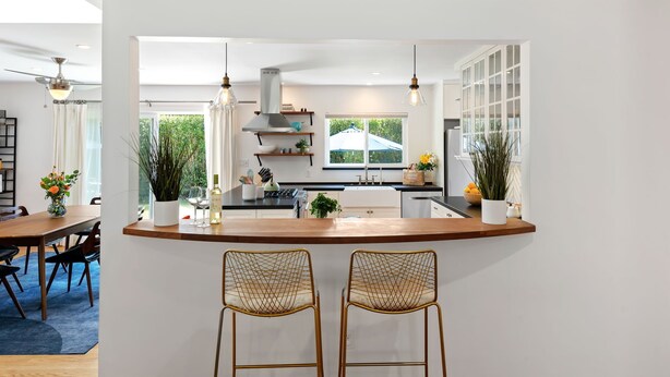 Una cocina moderna con una isla central, lámparas colgantes y vistas al exterior.
