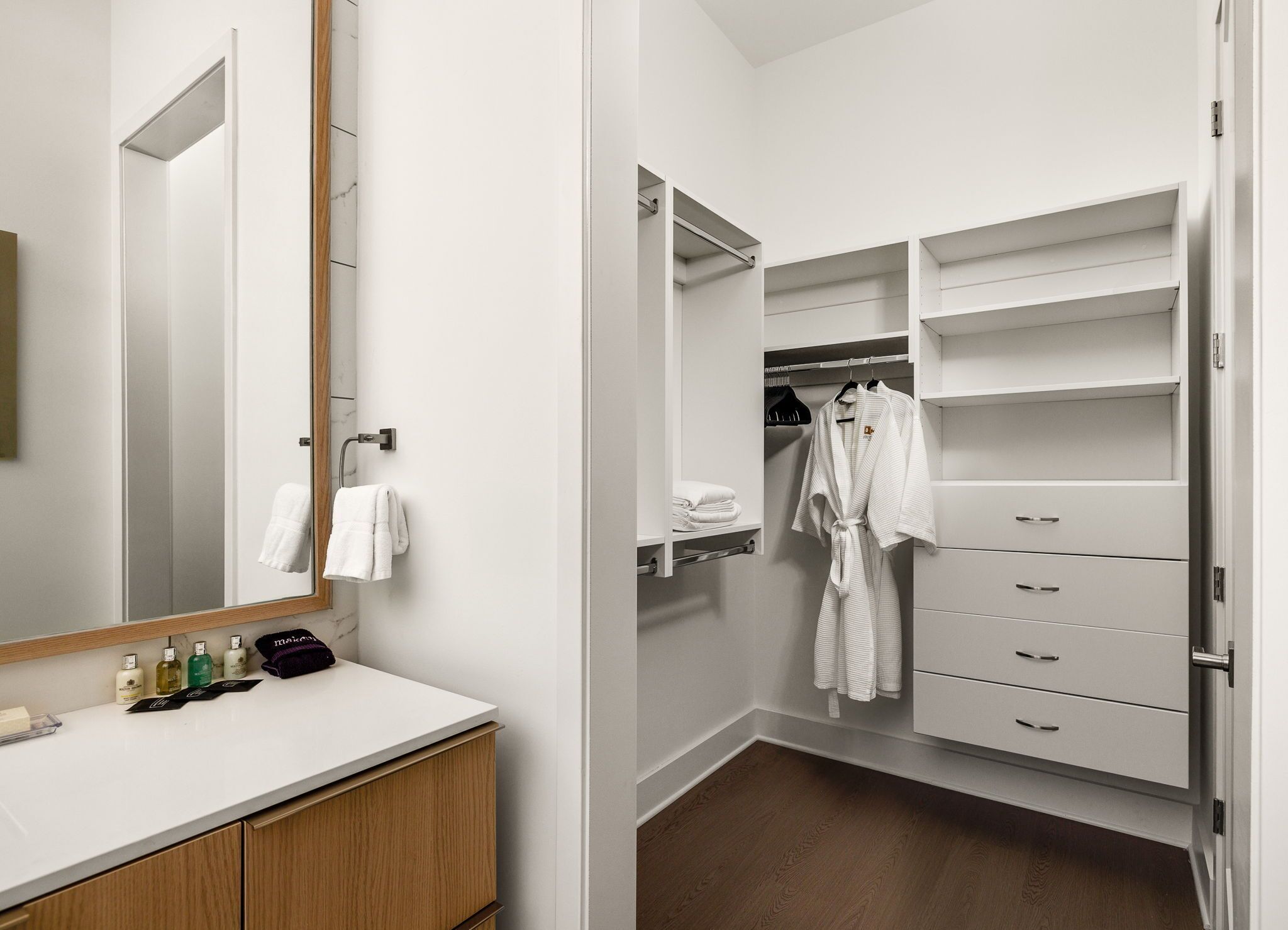 A modern bathroom with a white vanity, a large mirror, and a wooden cabinet.