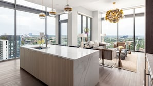 A modern kitchen with a marble island, large windows, and a city view. - 28th Floor Corner - Panoramic Penthouse by Atlanta Luxury Rentals (Atlanta)