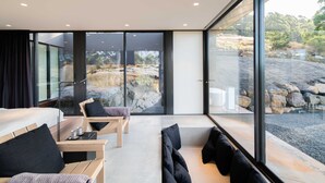 A modern room with a large window, a bed, a seating area, and a view of rocks and trees. - Mountain Top Snug Whole Property Itas (Snug)