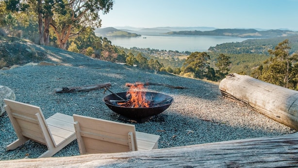 A campsite with a fire pit, two wooden chairs, and a log. - Mountain Top Snug, House Itas (Snug)