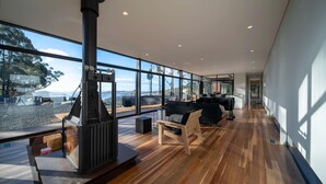 A modern interior with large windows, a fireplace, and a seating area. - Mountain Top Snug, House Itas (Snug)