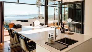 A modern kitchen with a large island, a sink, and a view of the landscape. - Mountain Top Snug, House Itas (Snug)