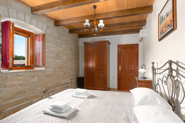 A bedroom with a bed, wooden wardrobe, and a window with curtains.