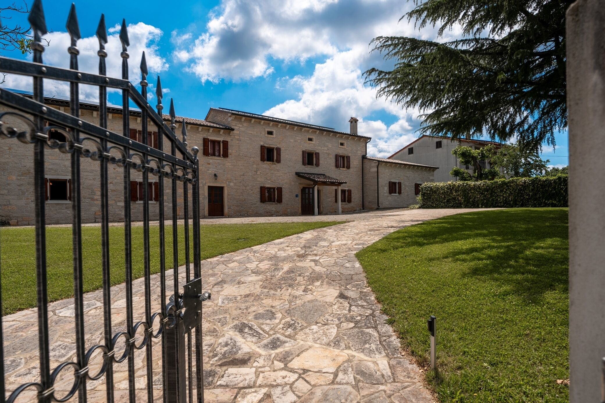 A stone pathway leading to a traditional stone building with a metal gate.