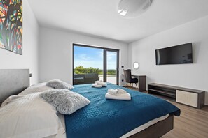 Relax in a spacious room with a large bed, flat-screen TV, and desk area.
